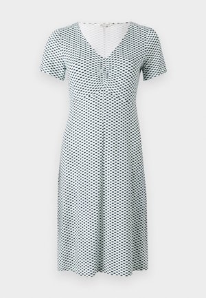 Kurzarmkleid in Weiß mit einem blauen geometrischen Muster. Hat einen V-Ausschnitt und Falten an der Brust, gefertigt aus einem weichen, dehnbaren Stoff.