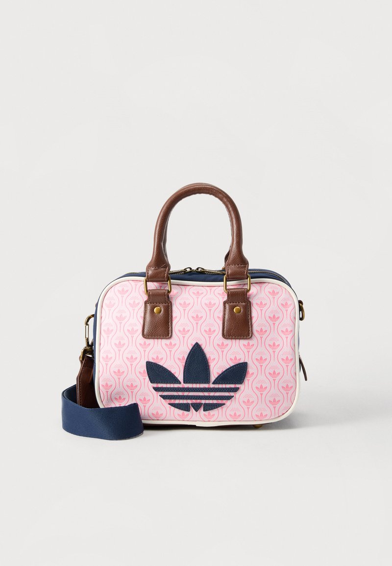 Μικρή ορθογώνια τσάντα με καφέ δερμάτινες λαβές, ύφασμα με ροζ σχέδια, λογότυπο Adidas σε σκούρο μπλε και αφαιρούμενο λουρί ώμου σε σκούρο μπλε.