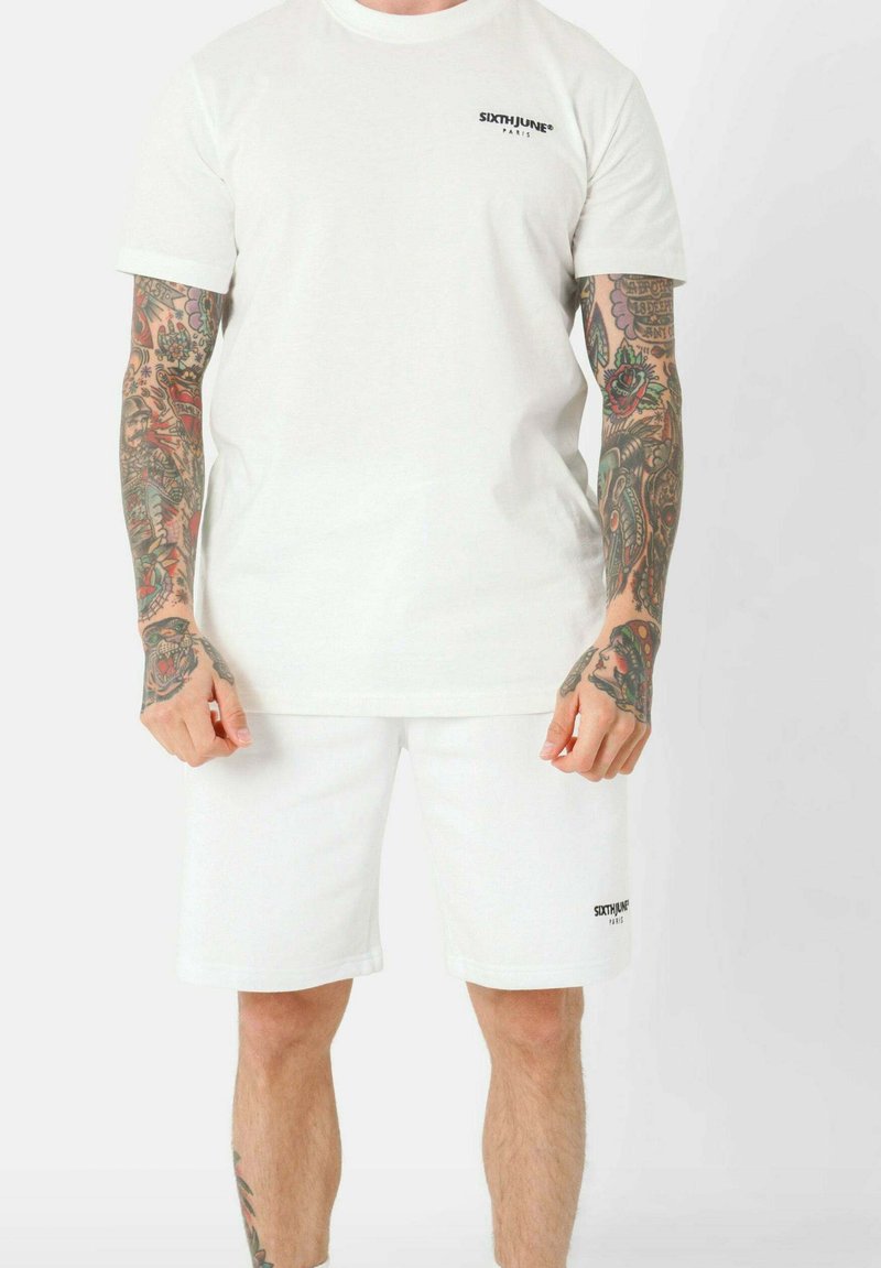 Set di maglietta e pantaloni corti in cotone bianco, con scollo a girocollo e maniche corte, caratterizzato dal logo nero "SIXTHJUNE" sul petto e sull'orlo dei pantaloni.