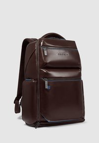 Zaino in pelle marrone con dettagli blu, dotato di più scomparti con cerniera, schienale imbottito e spallacci regolabili.