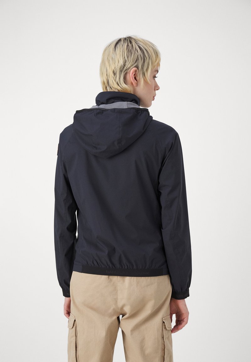 Giacca a vento navy con cappuccio, polsi e orlo elasticizzati. Presenta un tessuto leggero e una fodera in rete per la traspirabilità.