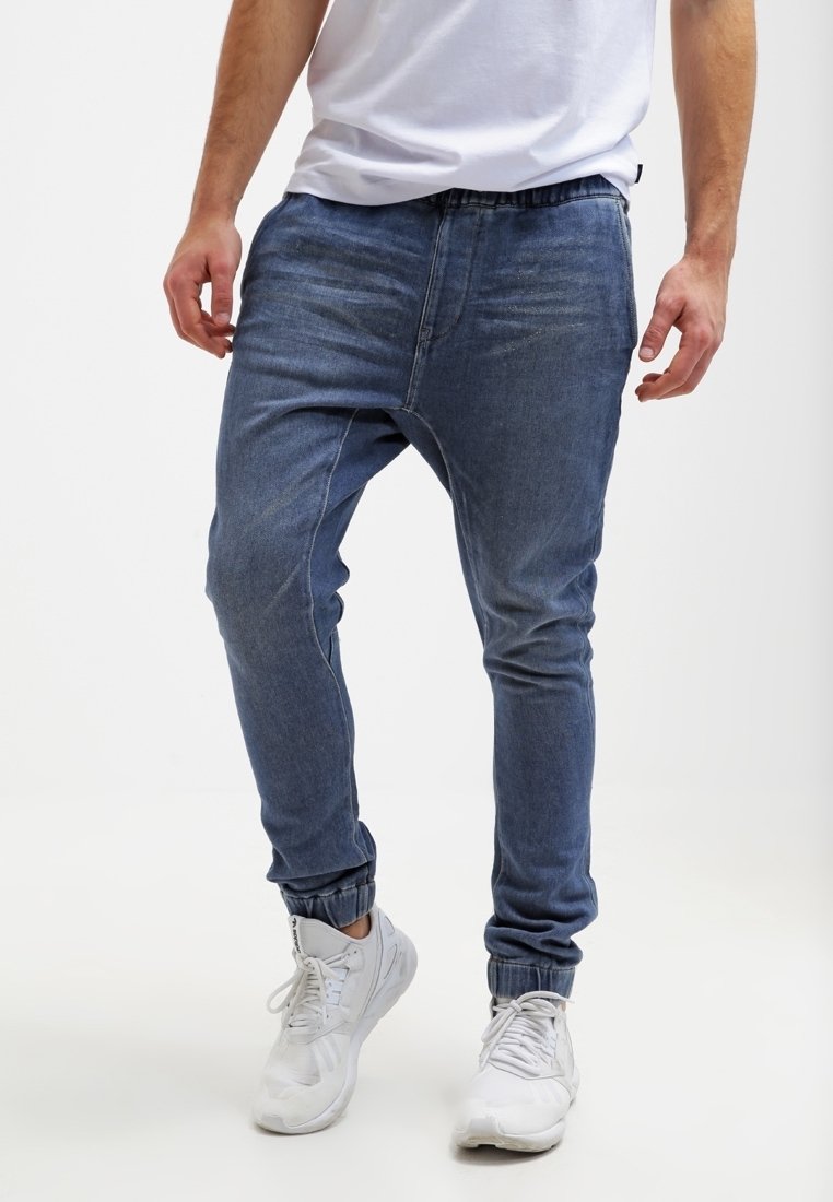 Džínové joggery v modré barvě, s elastickým pasem, manžetami na kotnících a volnějším střihem. Hladká textura s jemnými prvky vyblednutí.