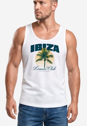 Man wearing a white tank top with a palm tree graphic and text "IBIZA Leisure Club" printed on the front, paired with blue jeans.