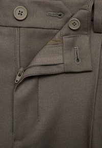 Bruine broek met ritssluiting en knoopsluiting, voorzien van zakken en zichtbare stiksels. De stof lijkt glad en duurzaam te zijn.