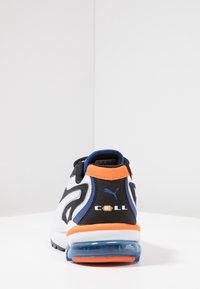 Baskets noires, blanches et orange avec une tige texturée, un talon rembourré et un amorti à air visible dans la semelle. Présente la marque "CELL".