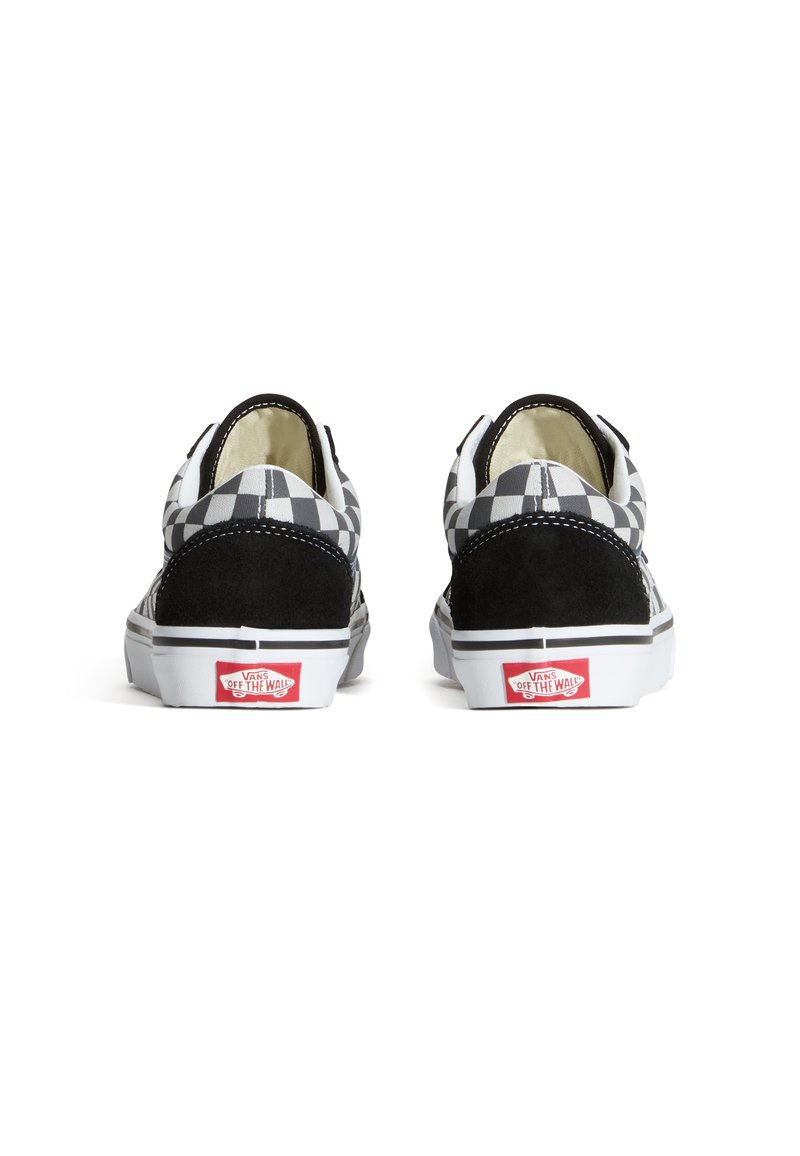 Zapatillas de lona a cuadros en blanco y negro con acentos de ante negro, suelas de goma blanca y un logo rojo en el talón. Diseño de perfil bajo.