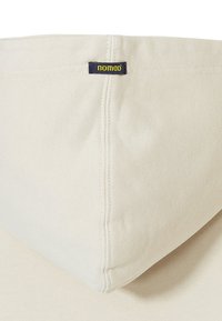 Crème-kleurige hoodie met een textuurstof, voorzien van een blauw label met "nomad" in het geel op de hals.