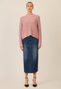 Pink ribbed knit sweater with a high neckline, paired with a blue denim midi skirt featuring dotted patterns, and black heeled shoes.