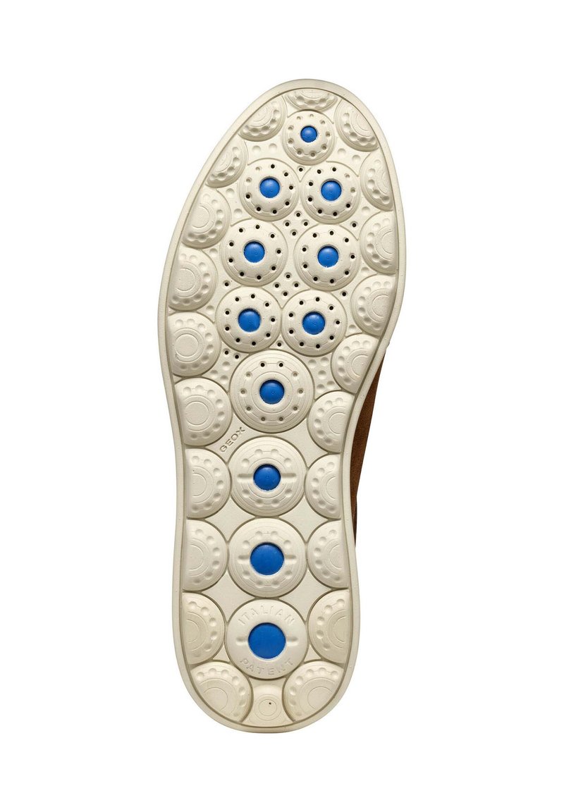 Semelle de chaussure avec une base en caoutchouc crème dotée de motifs de traction circulaires et de disques d'accent bleu, offrant une surface texturée pour une meilleure adhérence.