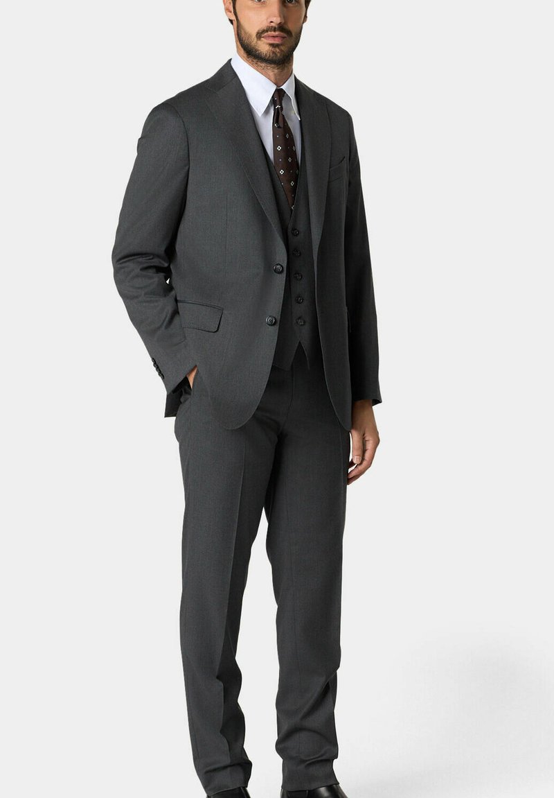 Koolgrijze drie-delige pak met een jasje met notch lapels, bijpassend vest en broek met platte voorkant. Een wit overhemd en een gedrukt stropdas maken de look compleet.