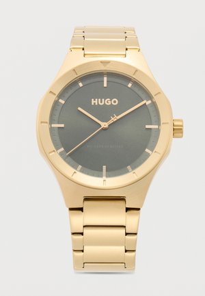 Goudkleurig Hugo polshorloge met een grijze wijzerplaat, minimale gouden uurmarkeringen en bijpassende gouden wijzers, die de tijd 10:10:40 weergeven.