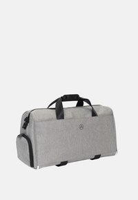 Grå duffelväska med svarta detaljer, topphandtag och en sidoficka; tillverkad av strukturerad tyg med rundad form.