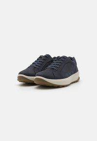Navy blue athletic shoes made of suede and mesh, featuring a low-profile design and light beige rubber sole with textured traction patterns.