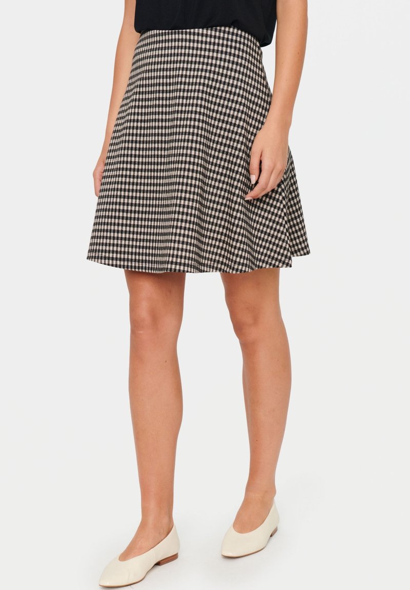 Svartvit rutig kjol med veck, tillverkad av lätt tyg, knälång, med en figurnära midja och svängig nederkant.