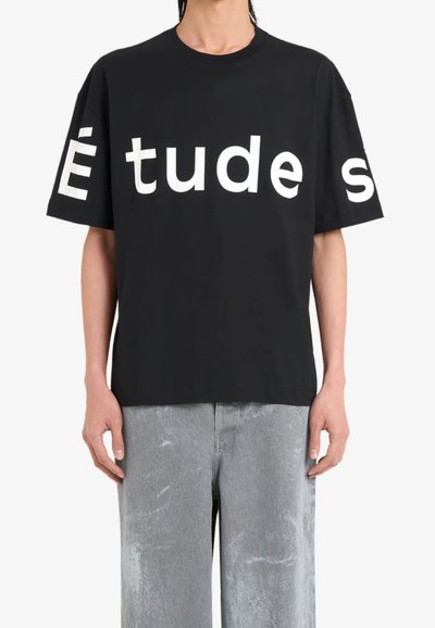 T-shirt en coton noir avec un grand lettrage blanc "Études" sur le devant. Encolure ronde, manches courtes, coupe décontractée et texture douce.