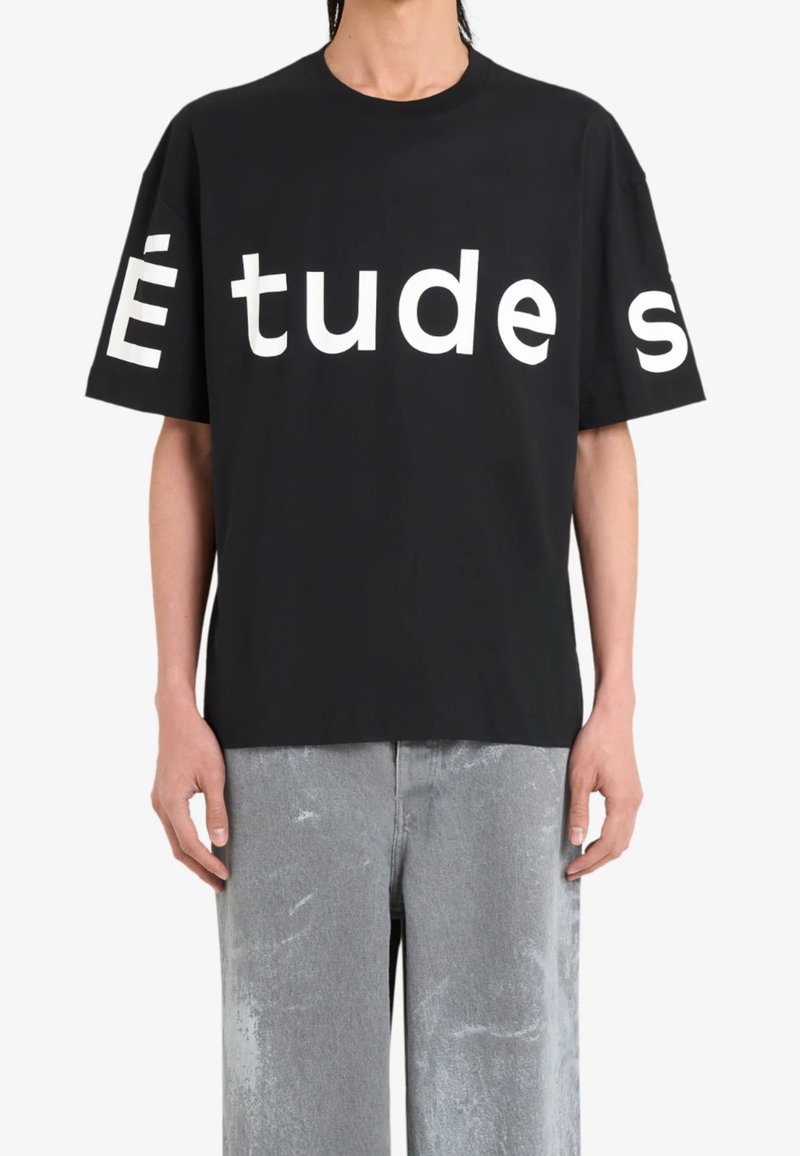 T-shirt en coton noir avec un grand lettrage blanc "Études" sur le devant. Encolure ronde, manches courtes, coupe décontractée et texture douce.