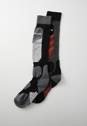 Knee-high socks made of blended fabrics featuring grey, black, and red colors, with varied patterns and textures, including reinforced toe areas.