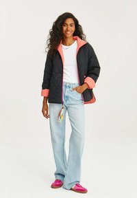 Černá prošívaná bunda s růžovými akcenty, zapínání na zip, v kombinaci se světle modrými zvonovými džíny a růžovými botami. Obsahuje barevný střapec.