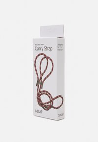 Correa de yoga trenzada, con un patrón en rojo y amarillo, con detalles metálicos para versatilidad, empaquetada en una caja blanca con detalles del producto.