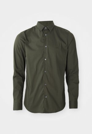 Long-sleeve shirt in dark green, made of smooth fabric, featuring a button-up front, collar, and subtle logo detail on the chest.