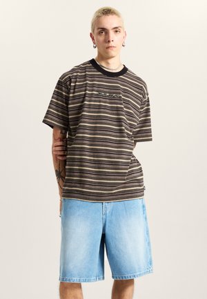 Striped short-sleeve T-shirt in shades of brown and cream with black trim and logo. Paired with light blue denim shorts. Smooth texture.