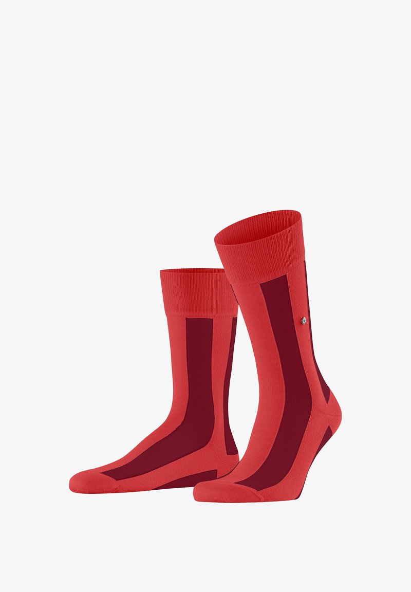 Paire de chaussettes rouges à bord-côte avec des rayures verticales rouge foncé, des bords côtelés et un petit emblème métallique sur le côté extérieur de chaque chaussette.