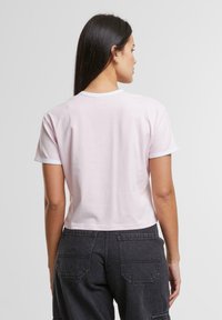 Kort rosa bomull t-skjorte med korte ermer, rund hals og kontrasterende hvit kant. Ryddig design uten synlige mønstre eller grafikk.