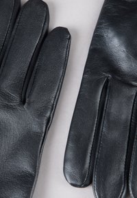 Black leather gloves with a smooth texture, featuring straight cuffs and stitched detail along the seams, laid on a light gray background.