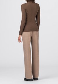 Bruine geribde lange mouw top gecombineerd met beige wijde broeken. De top heeft een getailleerd silhouet, terwijl de broeken een gestructureerde afwerking hebben.
