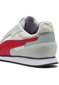 Puma sneakers med en grå og hvid overdel, røde læderdetaljer og en tekstureret grå hæl. Har en hvid og blå ydersål med "SOFTRIDE" branding.