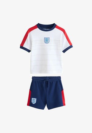 Wit shirt met korte mouwen met rode schouders en marineblauwe bies, gecombineerd met marineblauwe shorts met rode zijpanelen, beide met een blauw-wit embleem.