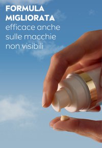 Flacone pompa bianco senza aria con un accentuazione dorata che eroga crema su una mano. Sullo sfondo si vede un cielo azzurro con nuvole leggere.