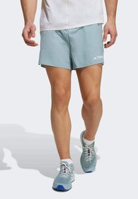 Pantalones cortos deportivos de color azul claro, hechos de material ligero, combinados con zapatillas deportivas azules claras a juego que cuentan con cordones y acentos blancos.