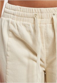 Cremfarbene Cord-Jogginghosen mit gerippter Textur, elastischem Bund und Kordelzug-Detail. Verfügt über seitliche Taschen für zusätzlichen Nutzen.