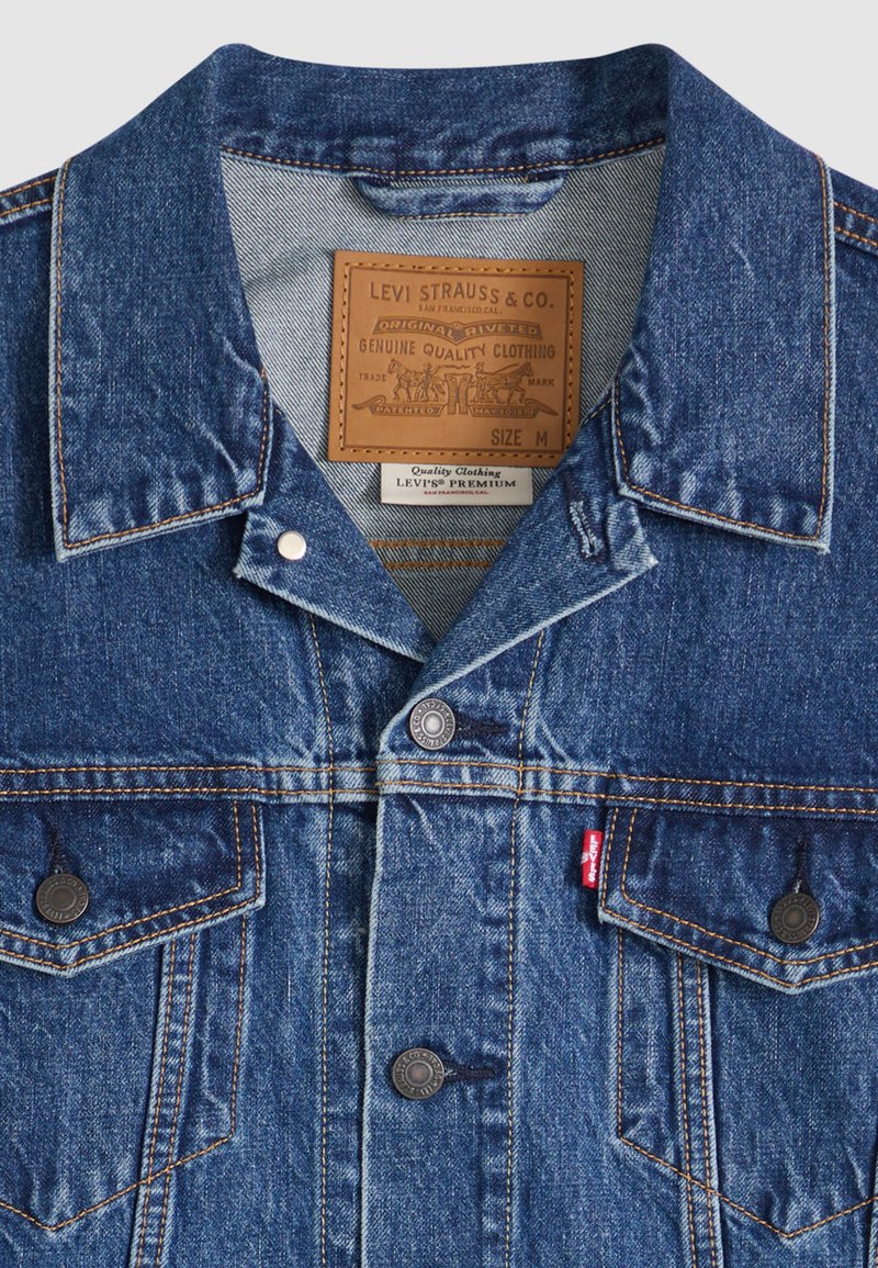 Jeansjacke in Dunkelblau mit einem Kragen, Brusttaschen, Messingknöpfen und einem Lederetikett innen. Klassisches Design.