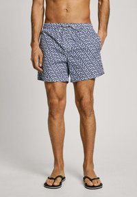 Costumi da bagno da uomo in blu navy con un motivo astratto bianco. Realizzati in tessuto leggero, presentano una vita elasticizzata e tasche laterali.