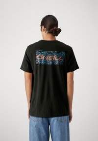 Camiseta de algodón negra con un diseño colorido y estampado en la parte posterior con texto estilizado. Manga corta y corte relajado.