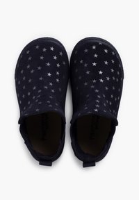 Zapatos slip-on azul marino con patrones de estrellas plateadas, hechos de ante, con una suela texturizada y una pestaña trasera para facilitar el calzado.