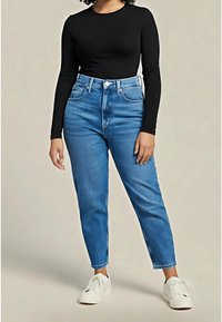 Černý top s dlouhým rukávem spojený s vysokými světlomodrými džíny a bílými teniskami. Džíny mají klasický design s pěti kapsami.