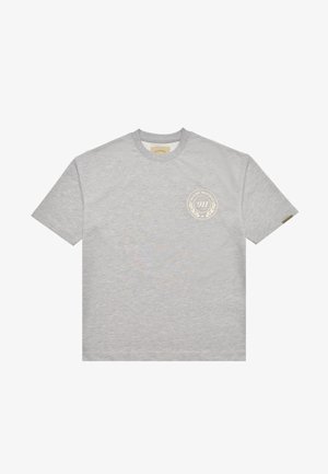 T-shirt grigio chiaro a maniche corte con scollo rotondo, caratterizzata da un piccolo logo circolare beige con la scritta "Pas de Monaco 911" sul lato sinistro del petto.