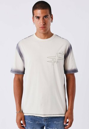 T-shirt in cotone beige chiaro con scollo rotondo, maniche corte e orlo sfumato. Design ricamato sul petto.