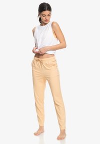 Lichtgewicht witte tanktop gecombineerd met zachte perzikkleurige joggingbroek met een elastische tailleband en trekkoord, een gladde textuur en een aansluitend ontwerp.