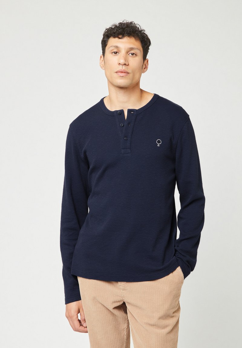 Maglietta henley a maniche lunghe di colore blu navy in tessuto testurizzato con placket a tre bottoni e logo ad albero ricamato sul petto sinistro.