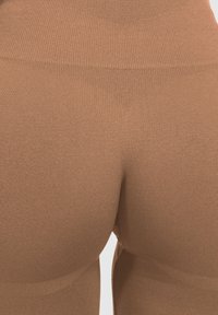 Bruine high-waisted leggings met een gladde, rekbare textuur; hebben een driehoekig accent aan de achterkant en een aansluitend ontwerp.