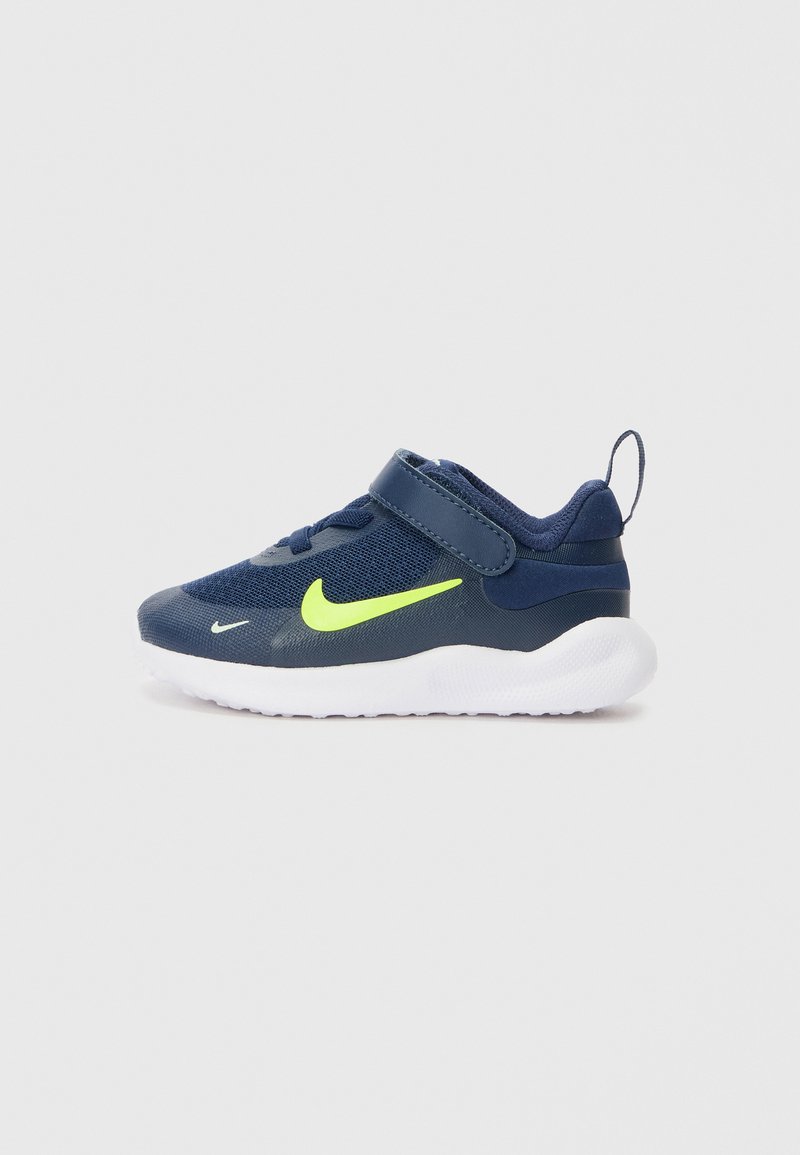 Dunkelblaue Sneakers mit Mesh-Obermaterial, neongelbem Swoosh, verstellbarem Riemen und weißer Sohle. Besitzt eine Zuglasche an der Rückseite für ein einfaches Anziehen.