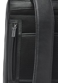 Zwarte leren tas met mesh inzetstukken, voorzien van een gezipte zak en gestikte accenten. De riem is breed en heeft een textuur voor grip.