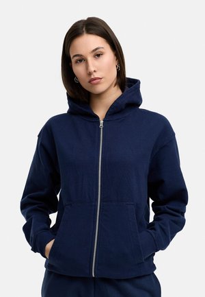 Navy zip-up hoodie made of soft fabric, featuring a kangaroo pocket, drawstring hood, and ribbed cuffs for comfort.