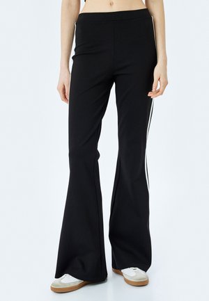 Zwarte flarebroek van rekbare stof met witte zijstreep. Heeft een hoge tailleband en een zachte textuur, geschikt voor casual kleding.