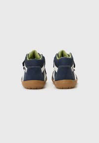 Navy blue high-top shoes with white accents, a textured fabric upper, and a gum rubber sole. Features padded green lining and adjustable strap.