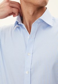 Camicia a righe blu chiaro e bianca con colletto classico, caratterizzata da una consistenza liscia e tre bottoni bianchi sullo sprone.